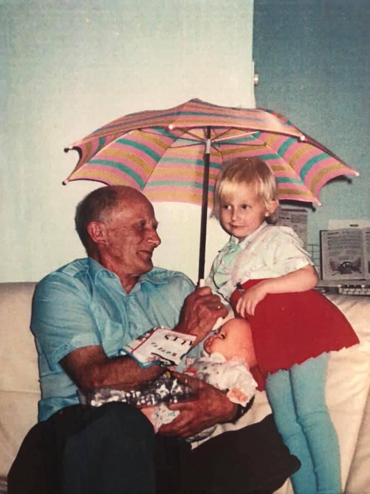 Hildegunn som liten jente sammen med en eldre mann i familien, under en fargerik paraply.