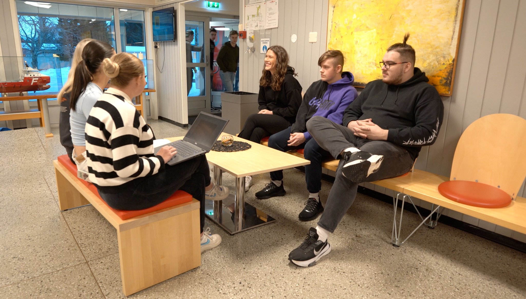 3 elever fra Herøy VGS sitter i en sofa på skolen.
