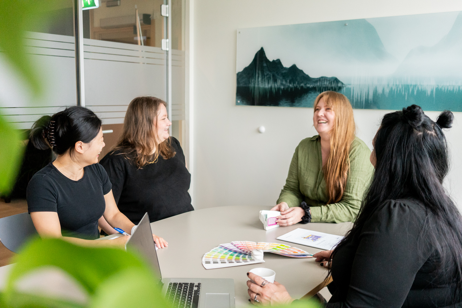 4 designere i en kreativ workshop. Fargevifte ligger på bordet. 