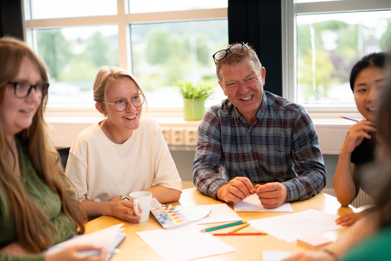 4 designere diskuterer et designarbeid i en workshop.