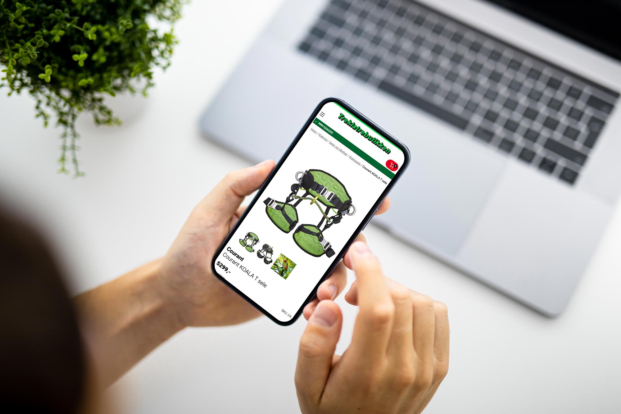 Hender som holder telefon med Treklatrenettbuitkk i hånda over en laptop