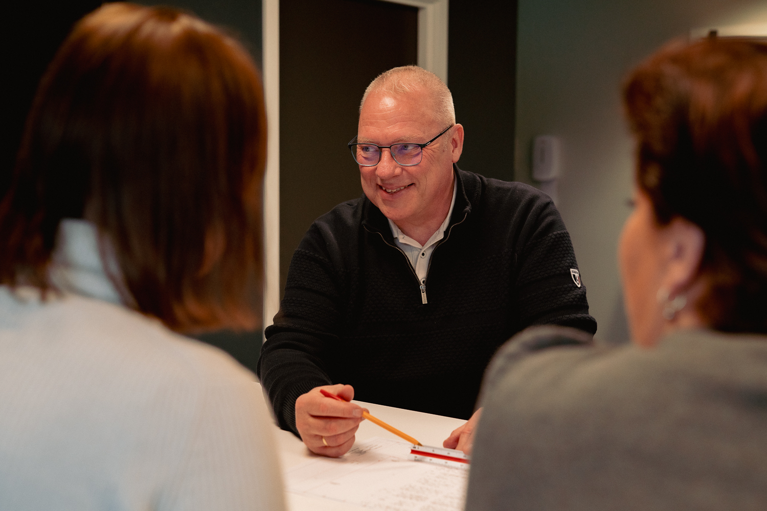Ansatte i Arena Service Team diskuterer tegninger rundt møtebordet