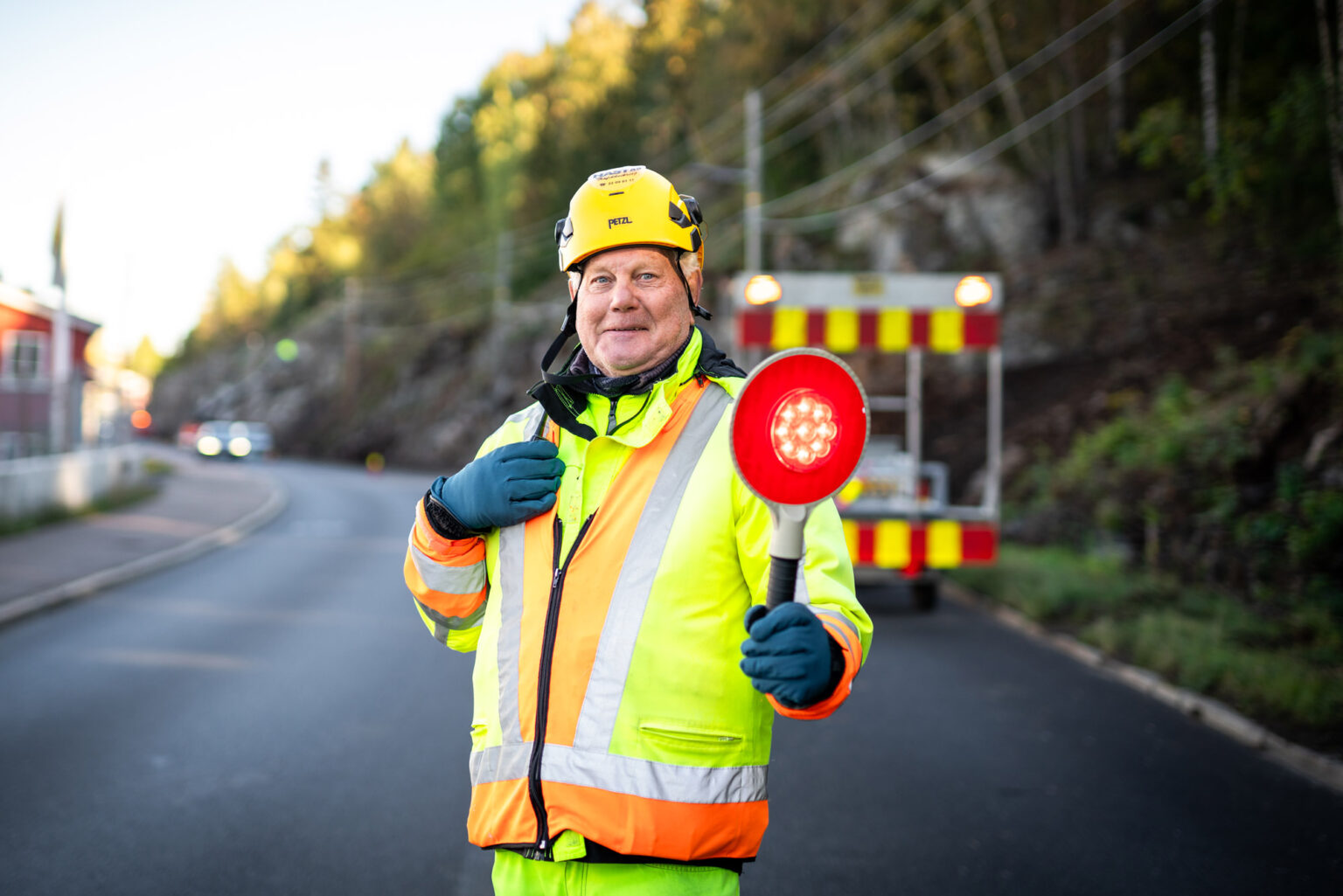 Trafikkdirigent fra Hast AS med lyssignal foran et sperrekjøretøy
