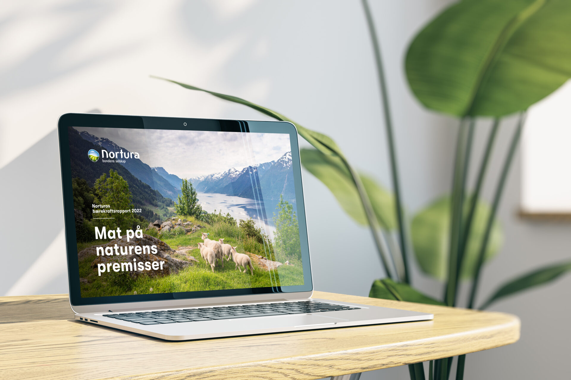 Norturas bærekraftsrapport 2022 vist på en laptop, med sauer i et norsk fjordlandskap på forsiden.