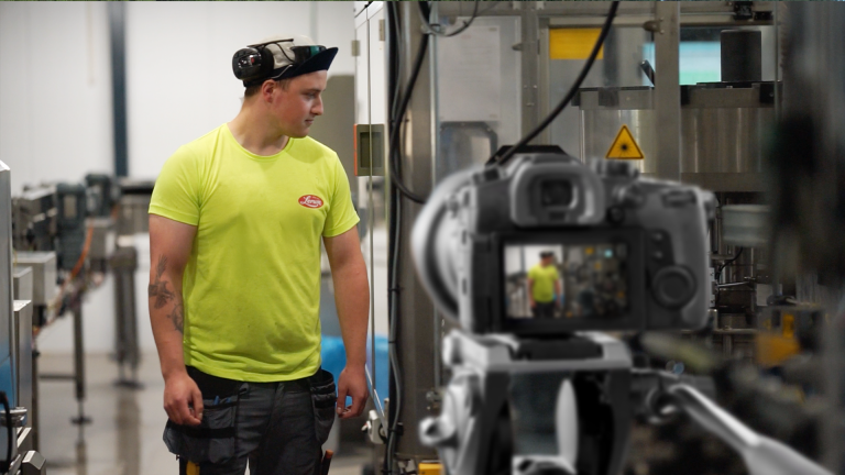 Ansatt i produksjonslokalene på Lerumfabrikken, med kamera og produksjonsutstyr i forgrunnen.
