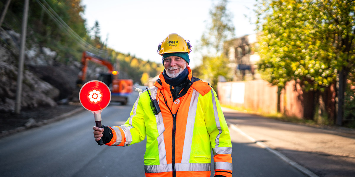 Trafikkdirigent fra Hast AS regulerer trafikken ved veiarbeid