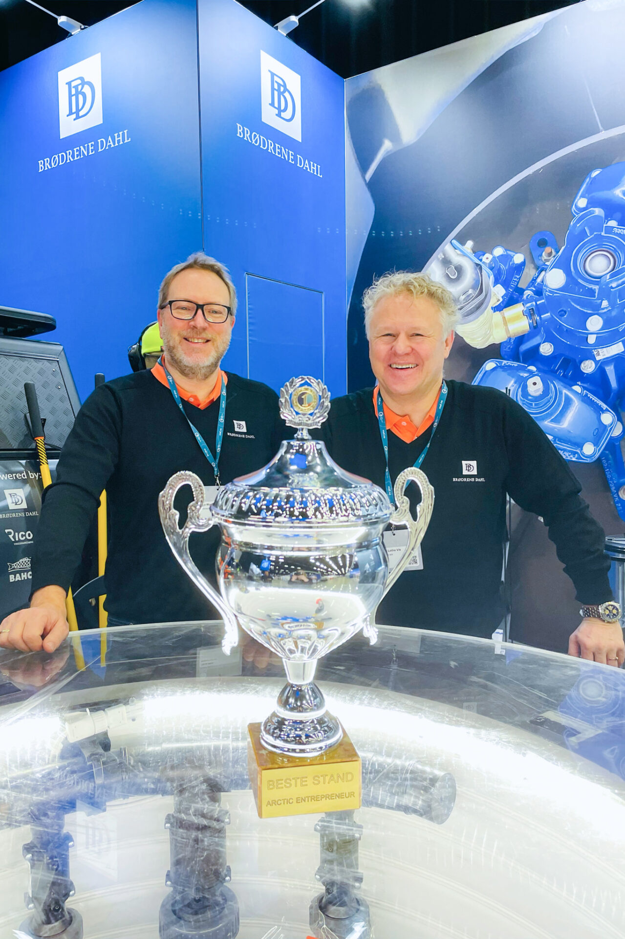 To kollega i Brødrene Dahl viser frem prisen de har vunnet for beste stand