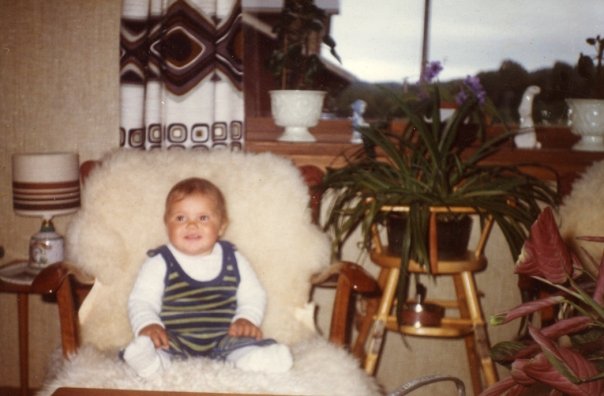 Stine som baby, sittende i en lenestol hjemme i stuen.